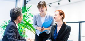 Three people from different nationalities sitting at a table and smiling